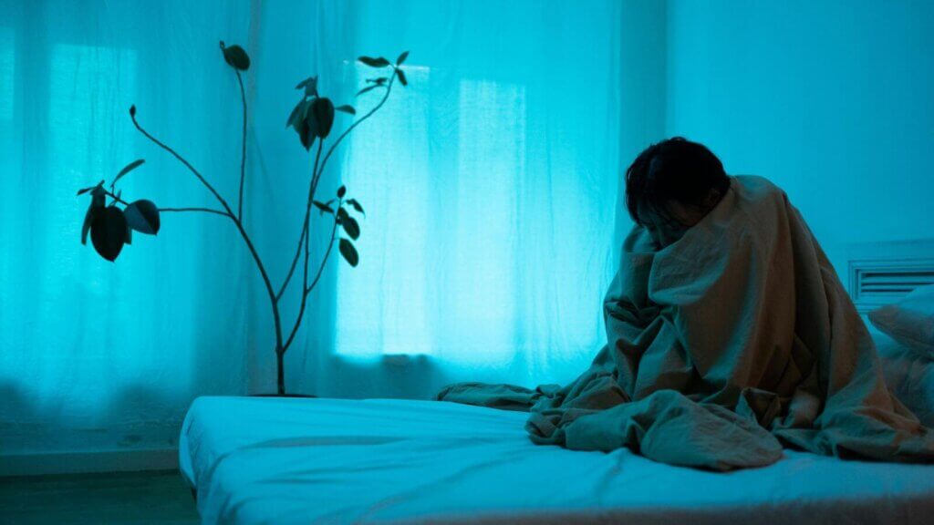 Pensamento negativo enquanto pessoa sentada na cama reflete sobre preocupações